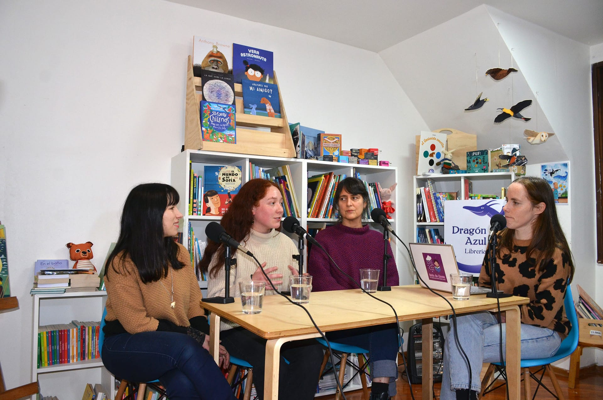 Marian Lutzky, Valentina Nielsen, Carolina Bruna y la conductora Cecilia Lagos sentadas frente a micrófonos de estudio dialogando sobre literatura en una librería.
